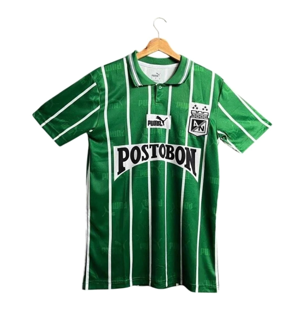 Camiseta de fútbol clásica retro de Atlético Nacional color verde con rayas verticales blancas, cuello polo y patrocinador Postobón.