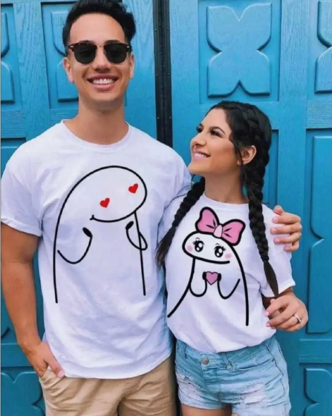 Pareja feliz sonriendo con camisetas blancas de Flork enamorado con ojos de corazón y moño rosa.